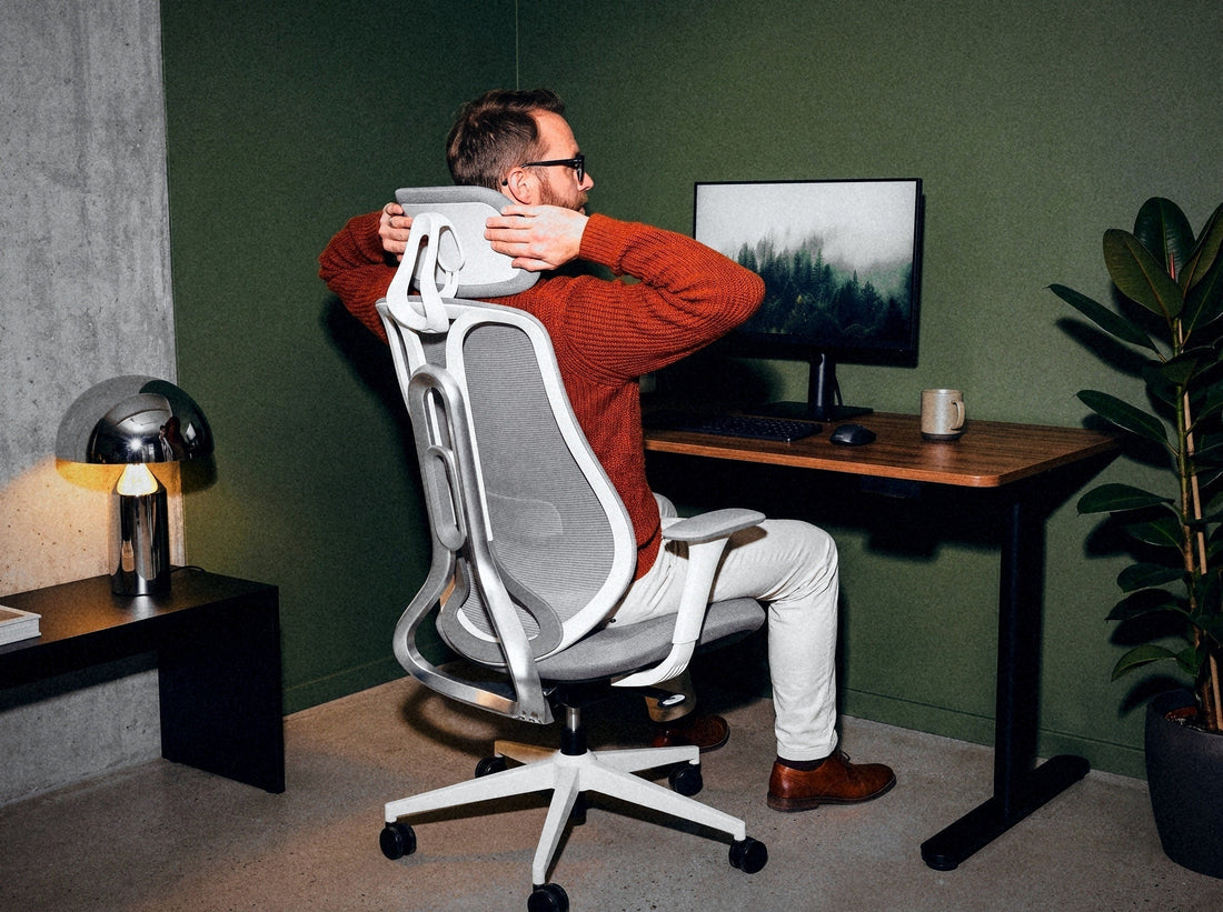 Mężczyzna siedzi w fotelu Ergonix OmniSit Pro i reguluje zagłówek, widok od tyłu